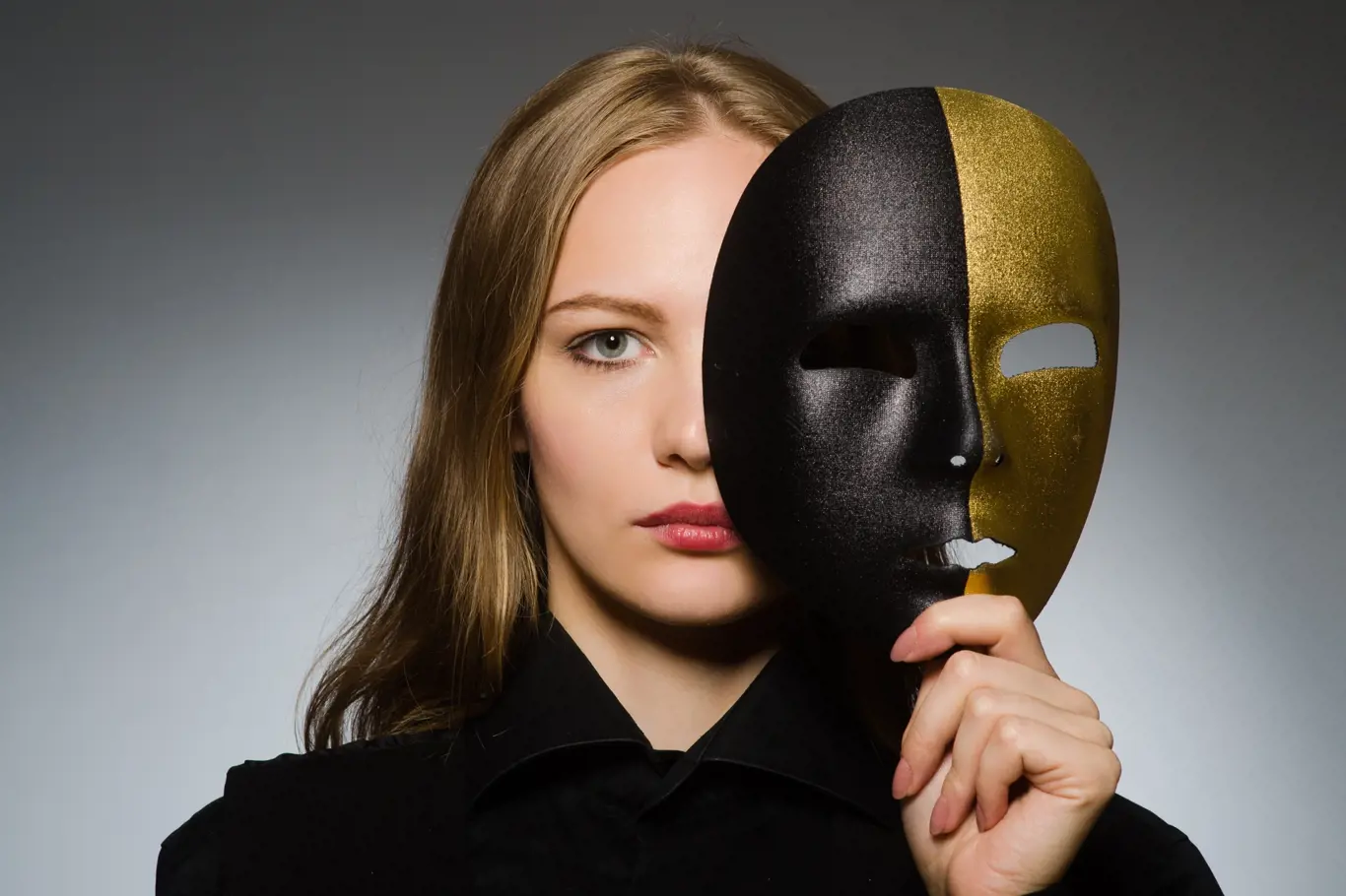 žena s vážnou tváří drží před obličejem masku