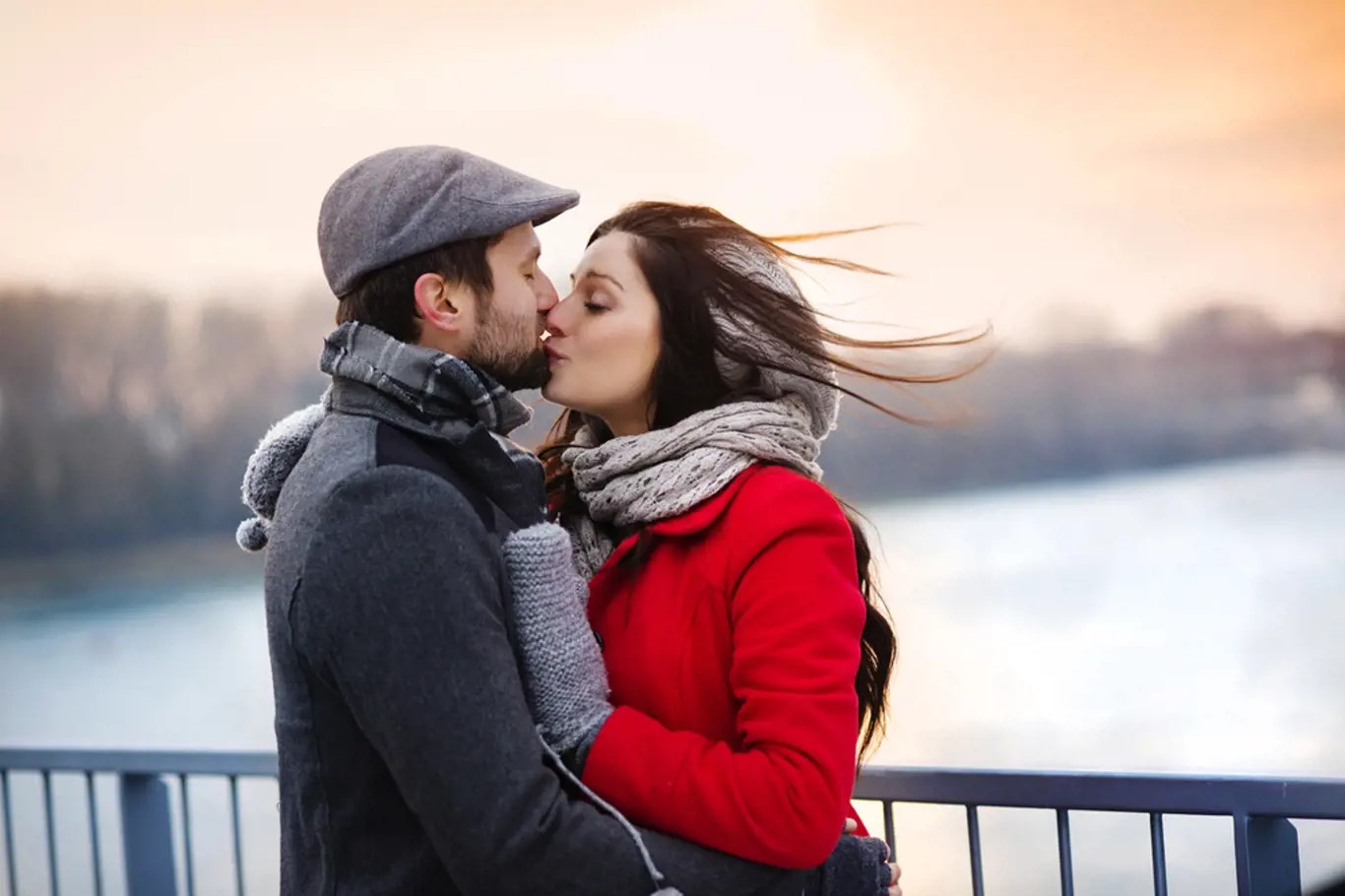 Young couple kissing by the river in winter weather