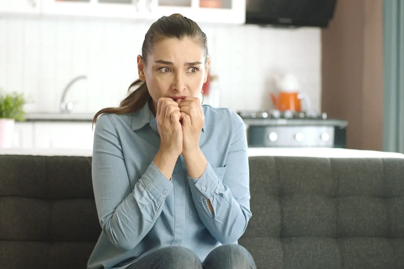 Nervous woman feeling panic, biting her nails, feeling anxious and confused. Frustrated and stressed woman waiting for someone at home. Angry woman biting her nails. Feelings of anxiety, fear.
