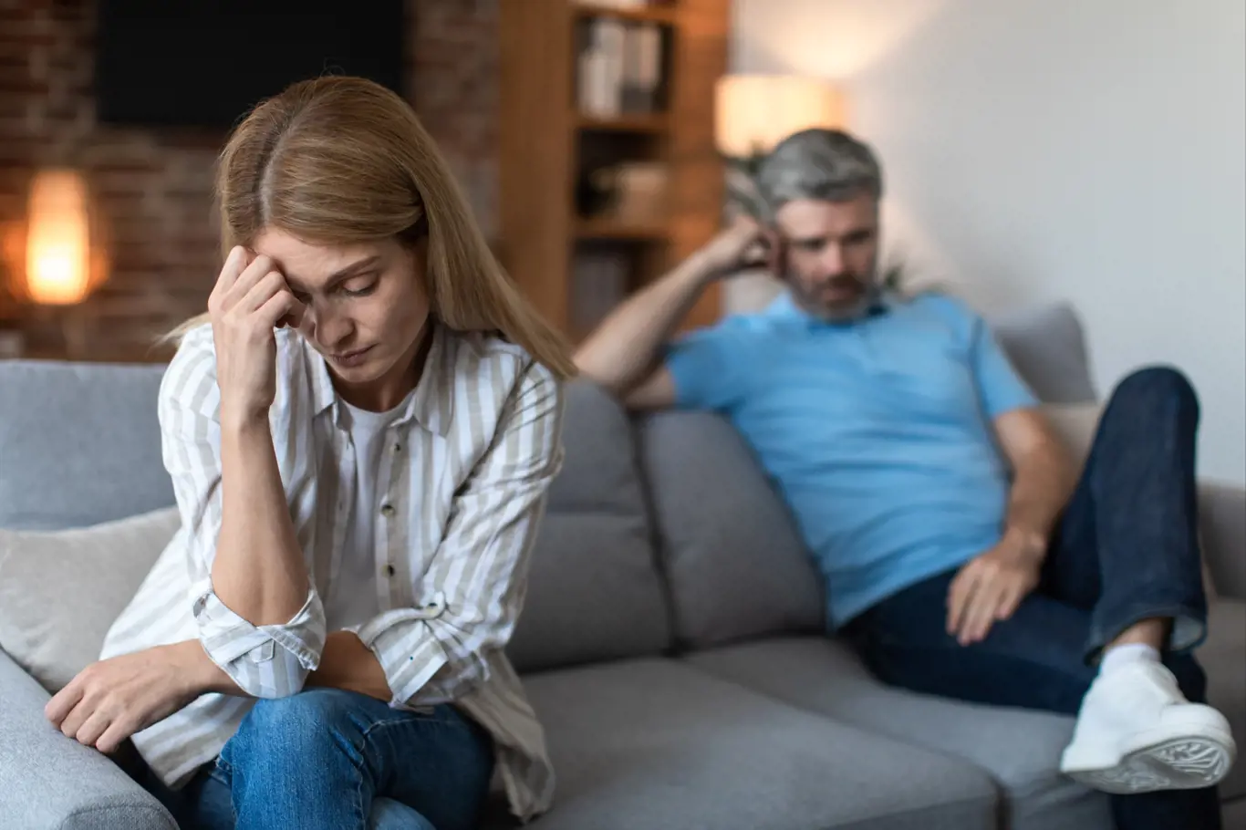 Upset middle aged caucasian male with beard ignores offended lady after conflict in living room interior. Quarrel, relationships problems, people emotions, depression, disagreement and stress at