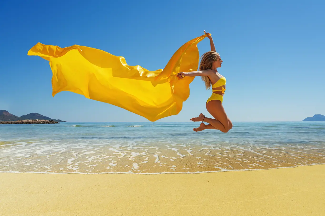 šťastná mladá žena na pláži ve žlutých plavkách