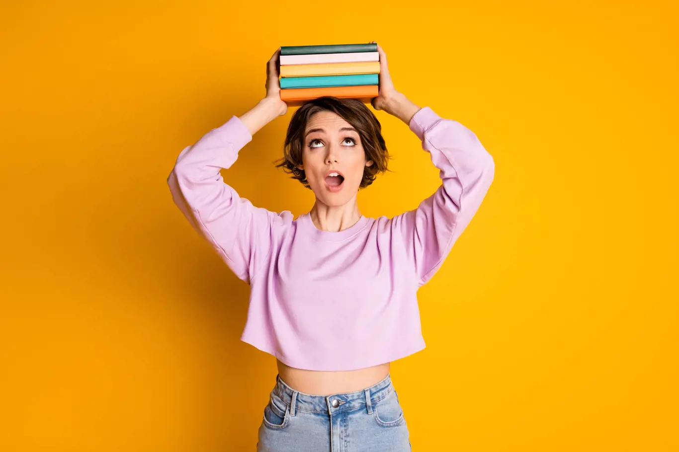 Portrait of astonished girl college student put copybooks on her head impressed how much material she need read prepare exam wear pullover isolated over bright color background