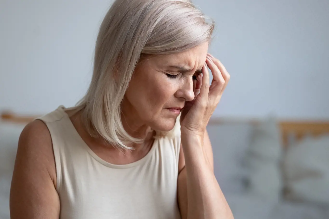 Close up of tired middle-aged woman touches face with hand having migraine or depression, frustrated old female troubled with personal or health problem feels stressed crying suffer from grief concept