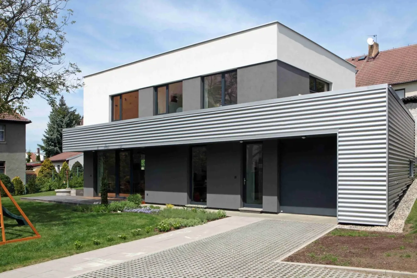 Ustupující druhé podlaží a povrchově i barevně strukturovaná fasáda opticky snižuje výšku domu.