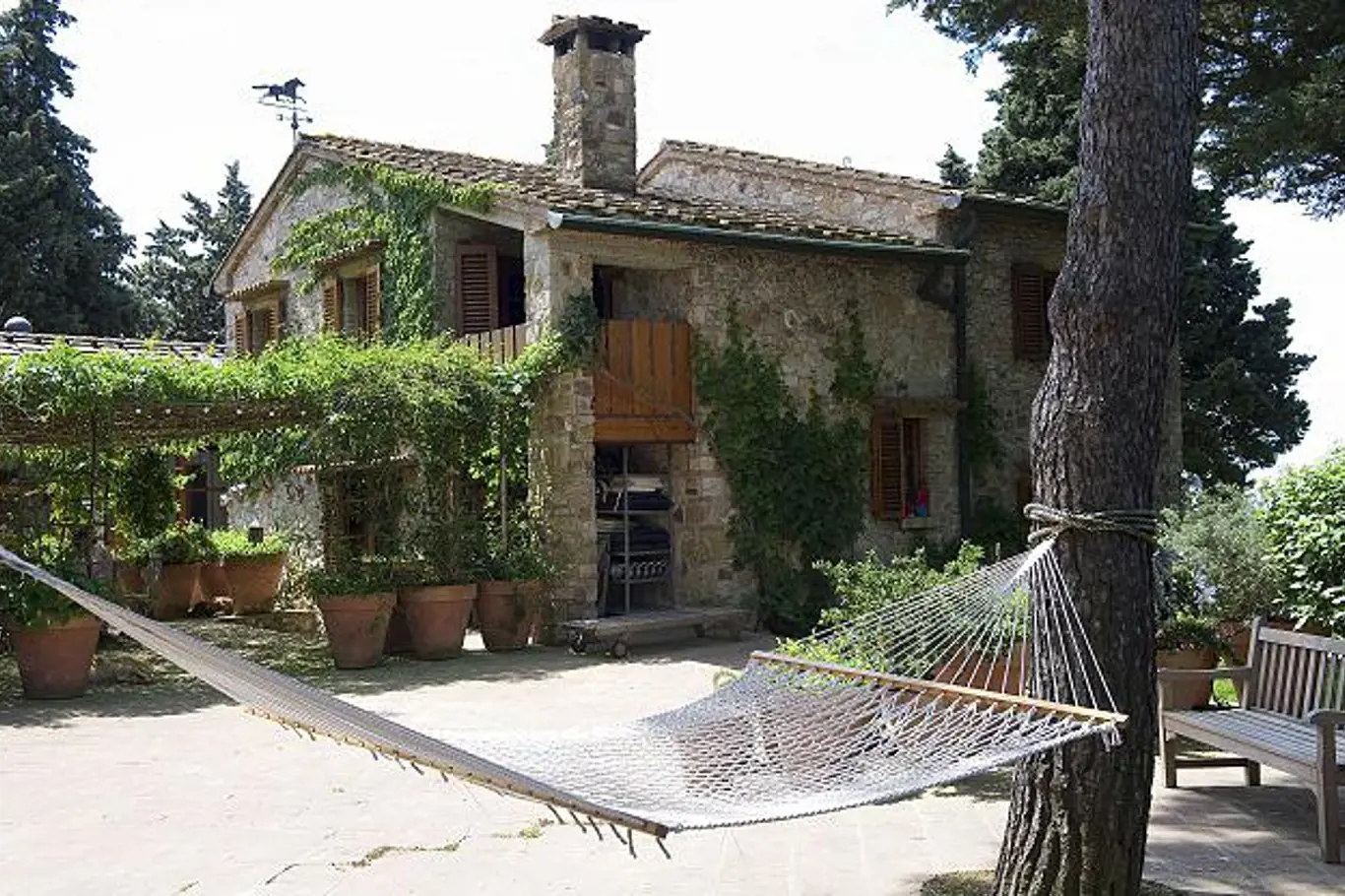 Tradiční kamenný dům středomořského typu s dřevěnými okenicemi a malou dřevěnou lodžií nad otevřeným vchodem.