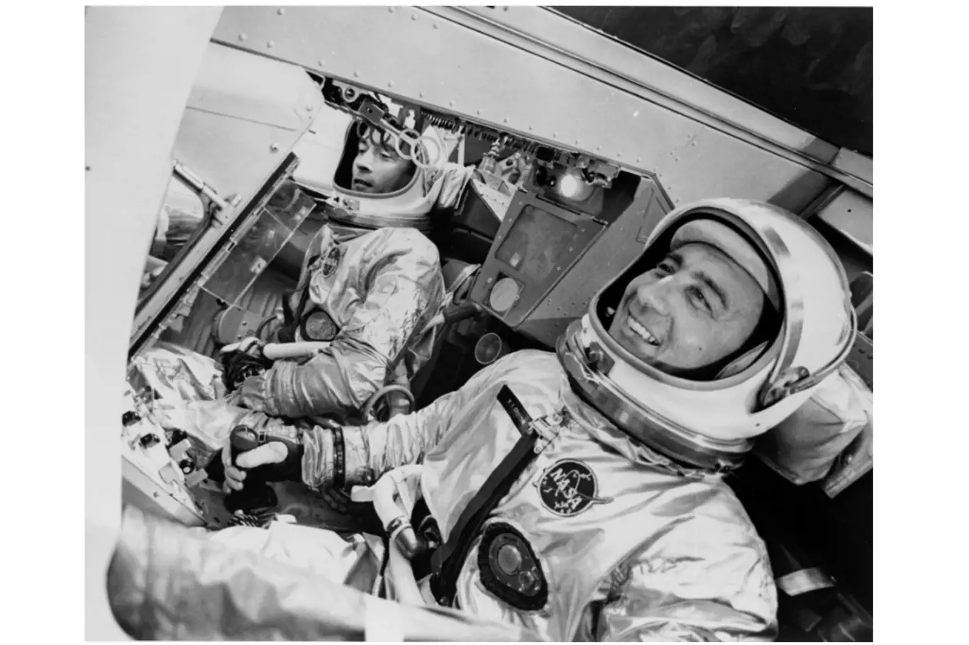 John Young (vlevo) a Gus Grissom letěli 23. března 1965 při prvním letu Gemini 3 s posádkou. Zde jsou zobrazeni v simulátoru kosmické lodi v továrně McDonnell v St. Louis. Jedním z dalších "pasažérů" skutečného letu byl sendvič s hovězím masem, který Young propašoval na palubu v kapse.