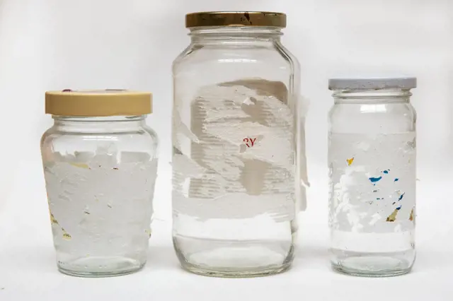 Removing sticky labels from glass jars. Hard to remove tags isolated on a white background