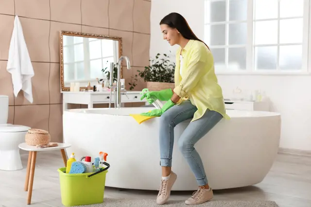 Beautiful young woman cleaning bathroom