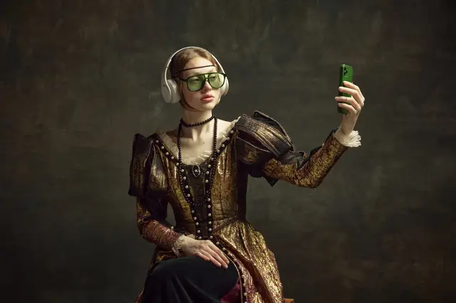 Portrait of young beautiful girl in vintage dress, trendy sunglasses and headphones, taking selfie with phone against dark green background. Concept of history, renaissance art, comparison of eras