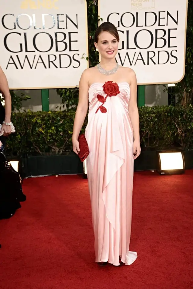 Natalie Portman si přišla pro druhý Zlatý glóbus v něžných šatech se stylizovanou červenou růží – stejnou barvu má také večerní kabelka. Hádali byste pod řasenou látkou bříško s miminkem?