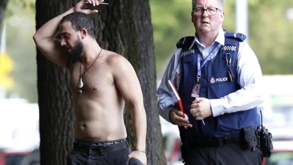 Policista doprovází jednoho z mužů, který uprchl před střelbou v mešitě v novozélandském Christchurch.