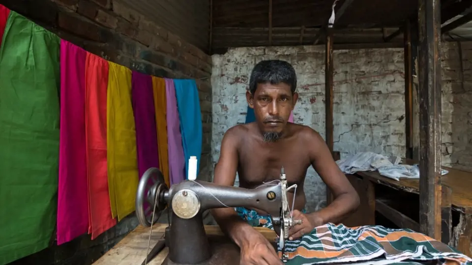 Muž v Dháce u šicího stroje