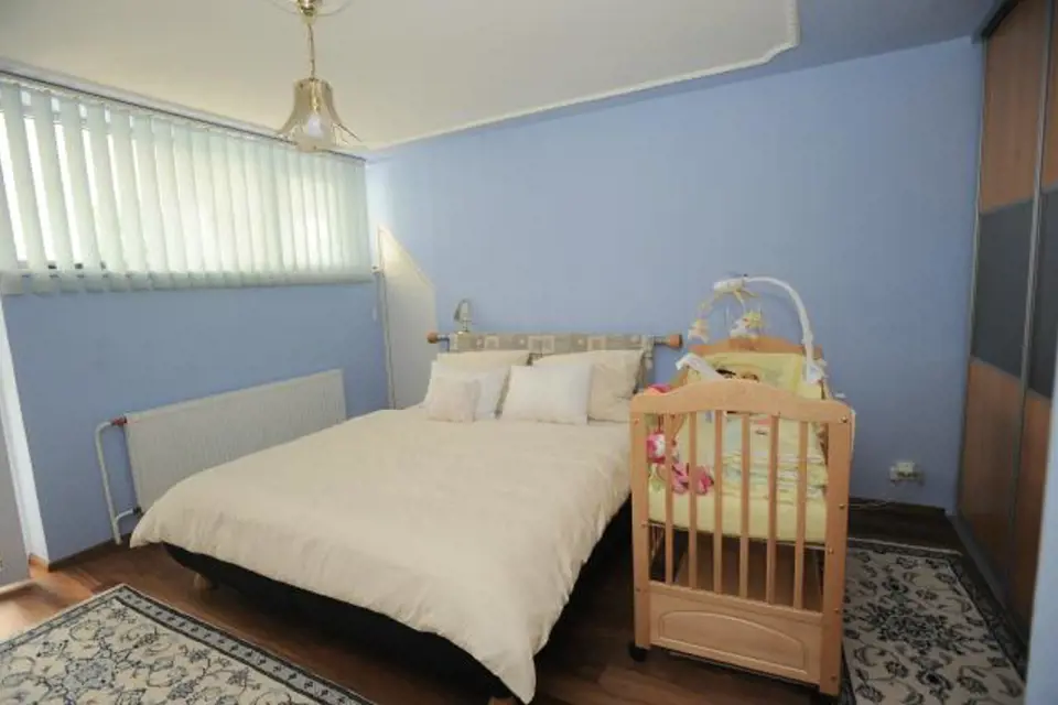 Modrá jednoduchá ložnice s nezbytnou dětskou postýlkou.