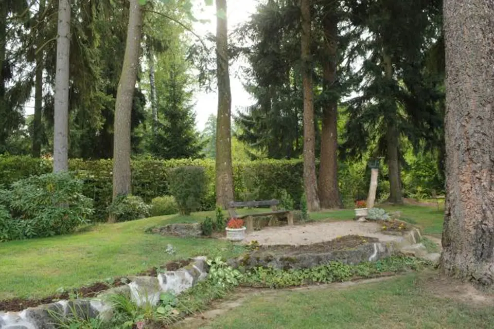 Dům se nachází v rozlehlé zahradě připomínající anglický park se vzrostlými jehličnatými stromy, jež vzbuzují představu lesa. 