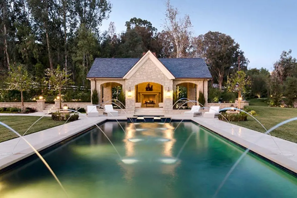 Bazén u domu Kim Kardashian spojuje hlavní vilu ze zahradním domkem. Po obou stranách malé osvětlené fontánky navozují romantickou atmosféru.