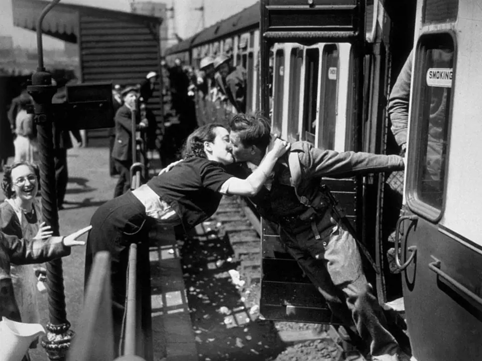 6. Mladá britská žena se naklání přes zábradlí, aby mohla políbit svého přítele, který se vrací z fronty, 2. světová válka, Londýn, 1940