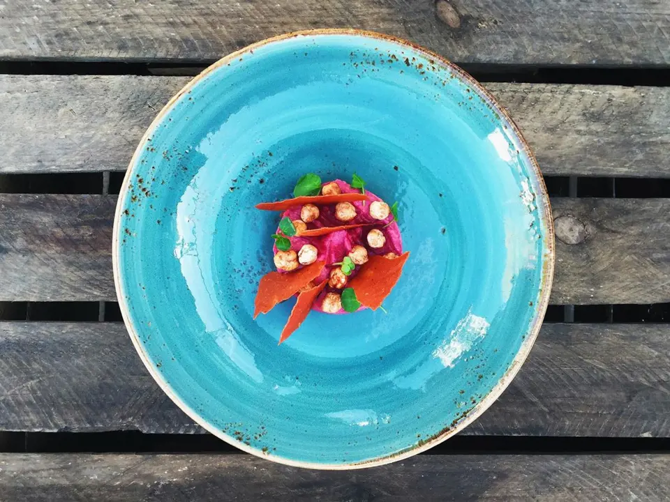 Minimalistický záběr jednoduchého jídla ozvláštní barva talíře a zajímavý povrch stolu