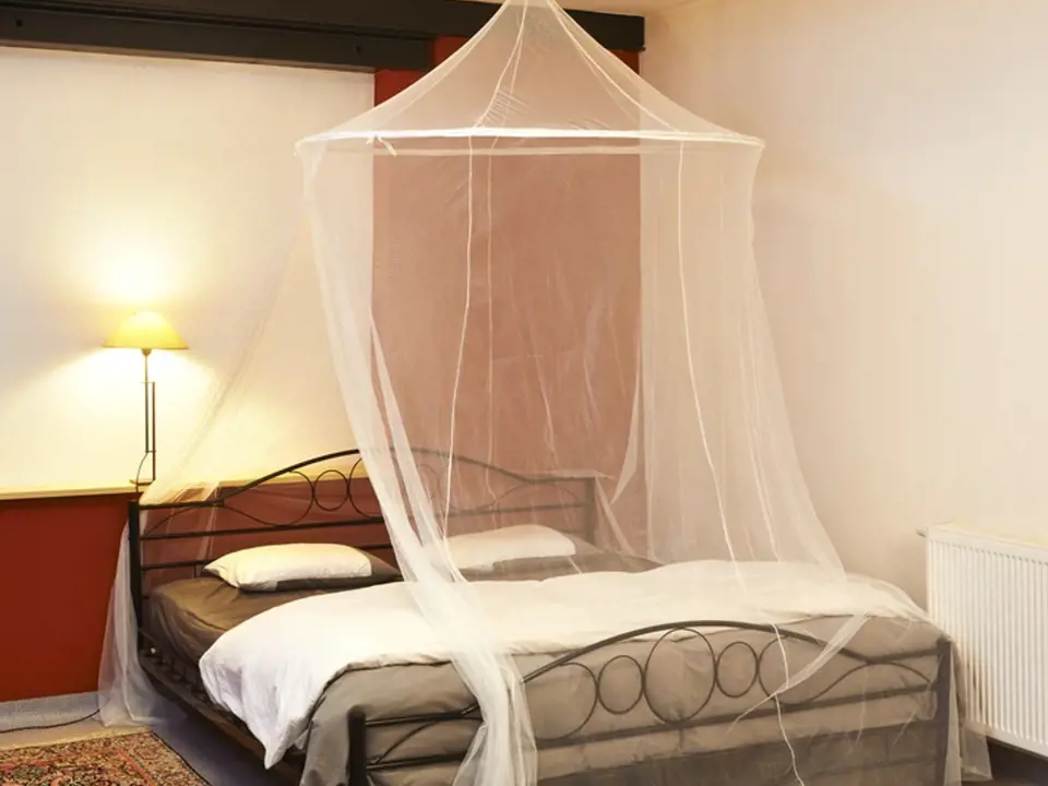 Lehká moskytiéra nad postelí může být účinnou ochranou proti komárům