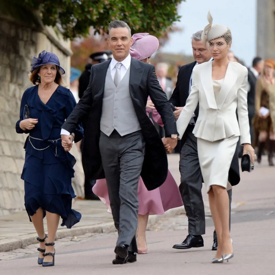 Robbie Williams vzal na svatbu nejen svou manželku, ale také maminku. Manželka Ayda oblékla kostýmek v odstínu slonovinové kosti a fascinátor. Maminka zvolila tmavě modré šaty s bohatými volány.